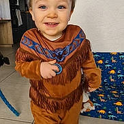 Aaron participe au concours pour gagner de l'argent avec cette photo : toddler, child, smiling, indoor, brown_outfit, fringes, blue_pattern, toy, slippers, dinosaur_print, floor_tiles, home, person, cute, happy, walking, young_child, playful, living_room, decor