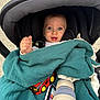 baby, stroller, blanket, toy_car, baby_bottle, smartphone, child, face, blue_eyes, hand, infant, outdoor, happy, portrait, person, clothing, seat, comfort, cute, small