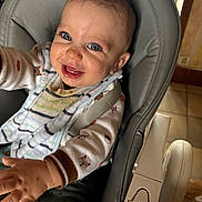 Tom participe au concours pour gagner de l'argent avec cette photo : baby, child, high_chair, bib, smiling, blue_eyes, messy_face, indoor, clothing, long_sleeve, patterned, seatbelt, reaching, happy, infant, person, cute, playful, furniture, home