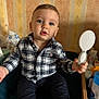 baby, child, plaid_shirt, mirror, indoor, sitting, curious, blue_eyes, wallpaper, toy, hand, footwear, sock, furniture, table, container, skin, face, person, expression