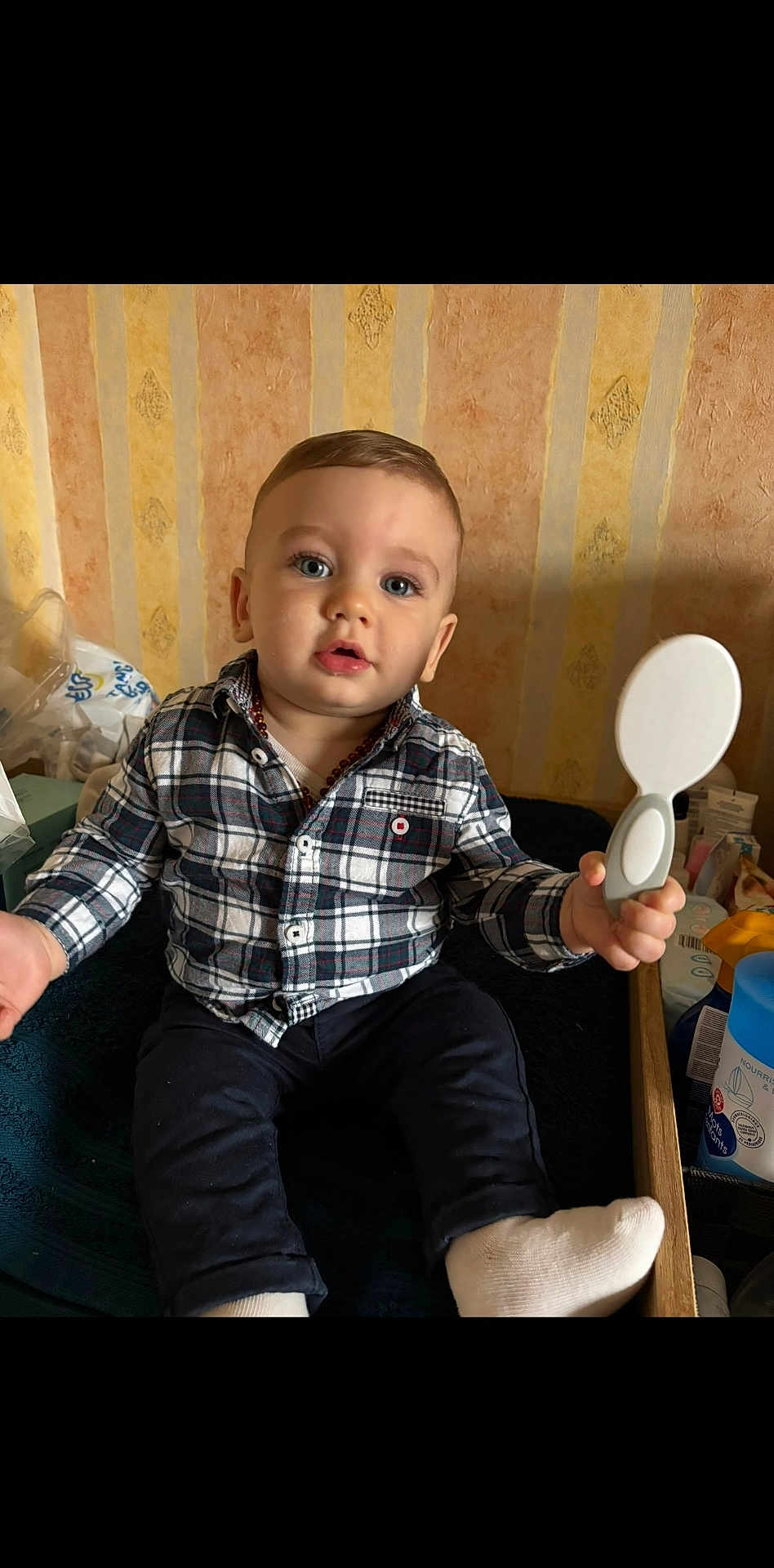 Tom a rejoint le concours — aidez-le/la à gagner de superbes lots ! baby, child, plaid_shirt, mirror, indoor, sitting, curious, blue_eyes, wallpaper, toy, hand, footwear, sock, furniture, table, container, skin, face, person, expression
