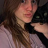 woman, cat, selfie, indoor, portrait, long_hair, black_cat, holding, face, eyes, casual_clothing, pouting, light_skin, pet, companion, close_up, expression, animal, human, friendship