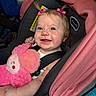baby, car_seat, child, cute, pink, plush_toy, pigtails, smiling, infant, seatbelt, happy, portrait, indoors, child_protection, soft_toy, clothing, person, face, hair_accessory, car_interior
