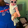 baby, child, sunglasses, beard, man, blue_hoodie, indoor, towel, clothing, person, holding, hand, face, portrait, furniture, cozy, casual, cute, fashion, funny