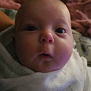 Isabella is registered to the contest to win money with this photo: baby, close_up, face, infant, wrapped, white_cloth, wide_eyes, cozy, blanket, soft_lighting, indoor, person, cute, portrait, newborn, expression, child, head, skin, sleepy