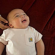 Ashton joined the competition — help win amazing prizes! baby, infant, smile, white_shirt, hand, blanket, red_blanket, happy, portrait, lying_down, cute, chubby_cheeks, child, toddler, skin, clothing, person, indoors, close_up, head