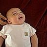 baby, infant, smile, white_shirt, hand, blanket, red_blanket, happy, portrait, lying_down, cute, chubby_cheeks, child, toddler, skin, clothing, person, indoors, close_up, head