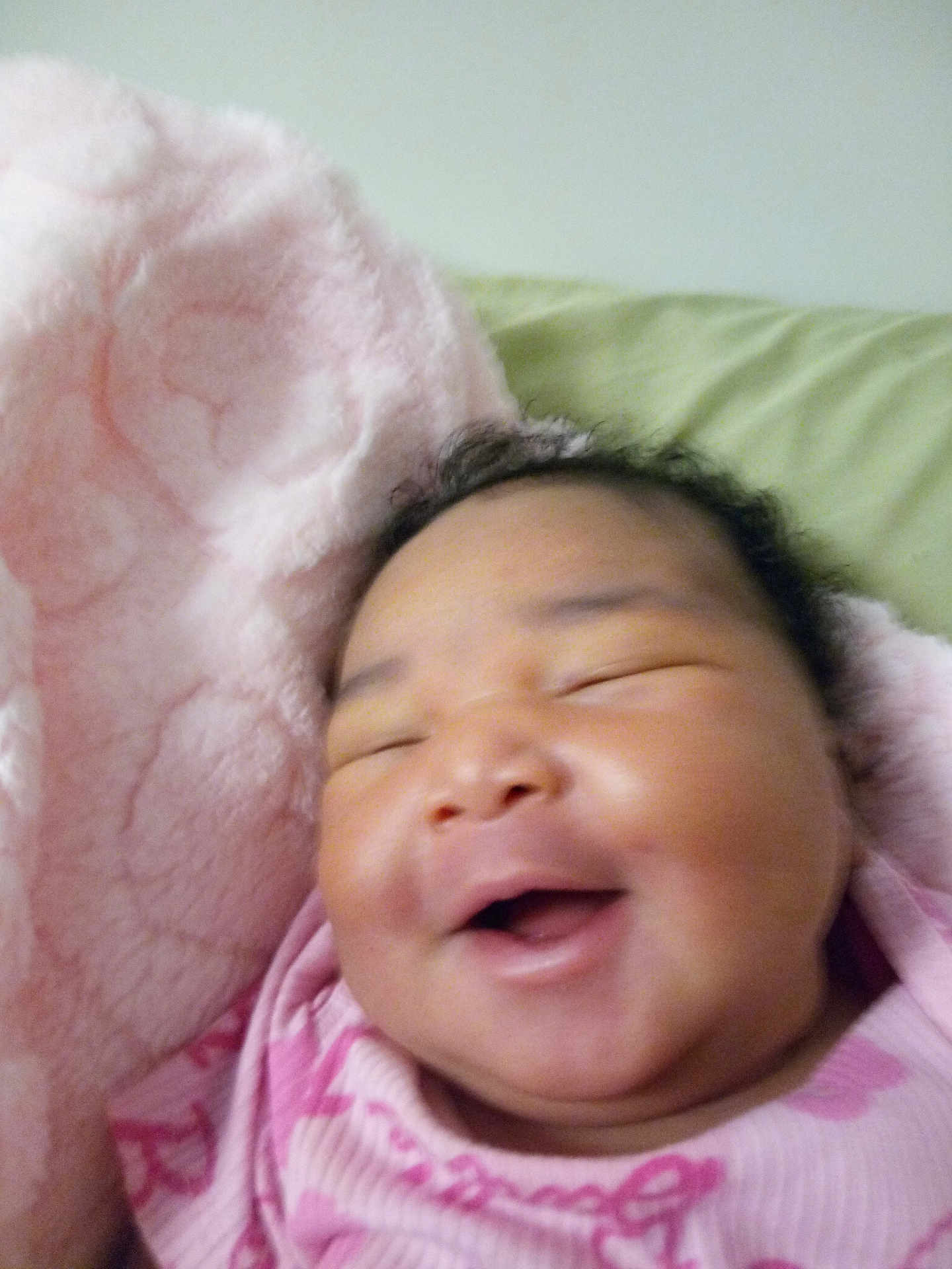 Queen is registered to the contest to win money with this photo: baby, smiling, face, infant, pink_blanket, pink_clothing, sleeping, happy, closeup, child, soft_texture, cozy, portrait, cute, indoors, resting, head, skin, young_child, toddler