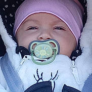 Leya participe au concours pour gagner de l'argent avec cette photo : baby, pacifier, beanie, white_jacket, car_seat, child, face, infant, cute, bundle, warm_clothing, pink, black, seatbelt, hooded_jacket, expression, portrait, closeup, winter_wear, sun_design