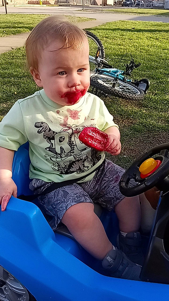 Jedidiah is registered to the contest to win money with this photo: automotive_tire, baby, baby_toddler_clothing, bicycle_wheel, child, cool, fun, grass, happy, human_leg, lap, leg, leisure, person, recreation, shorts, sitting, thigh, tire, toddler
