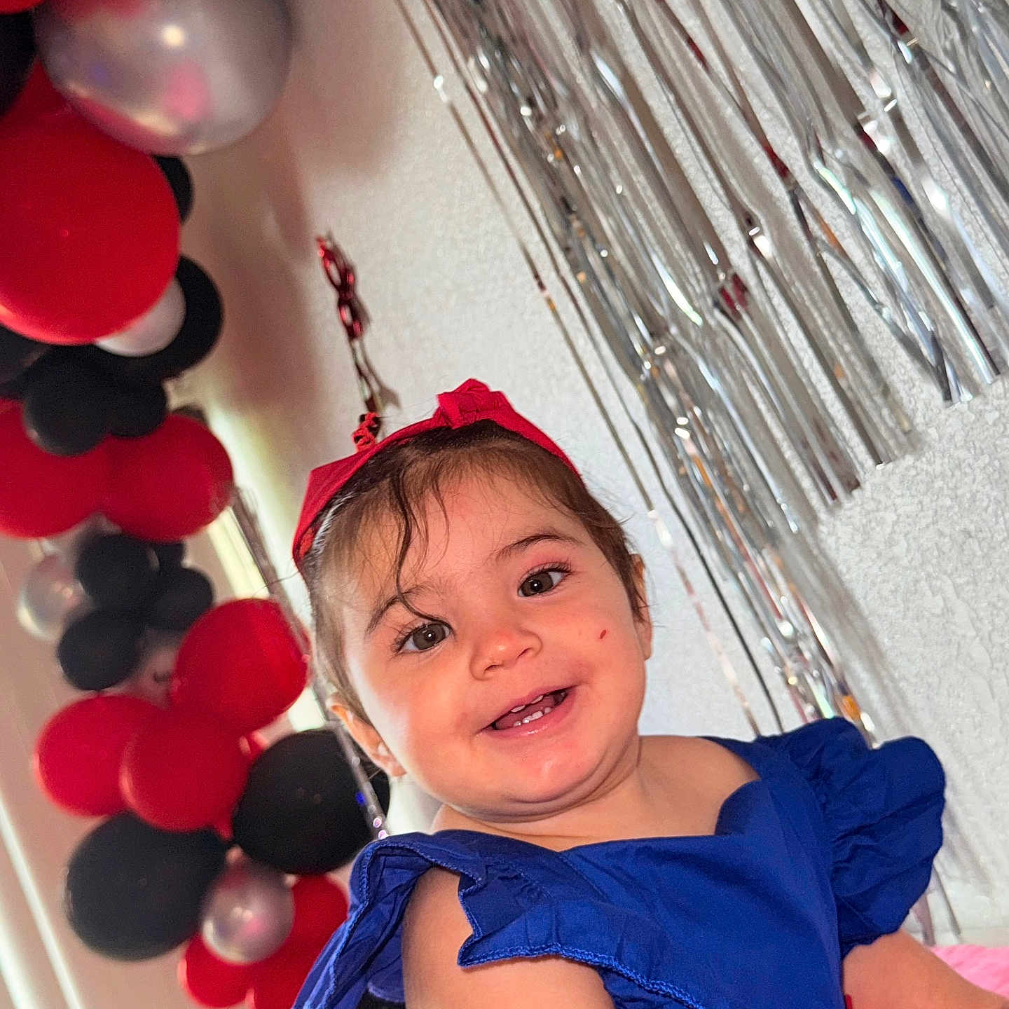 Aleska Castellano joined the competition — help win amazing prizes! balloons, blue_dress, celebration, child, colorful, cute, decorations, face, festive, happy, indoor, joyful, party, person, portrait, red_headband, silver_streamers, smiling, toddler, young_child