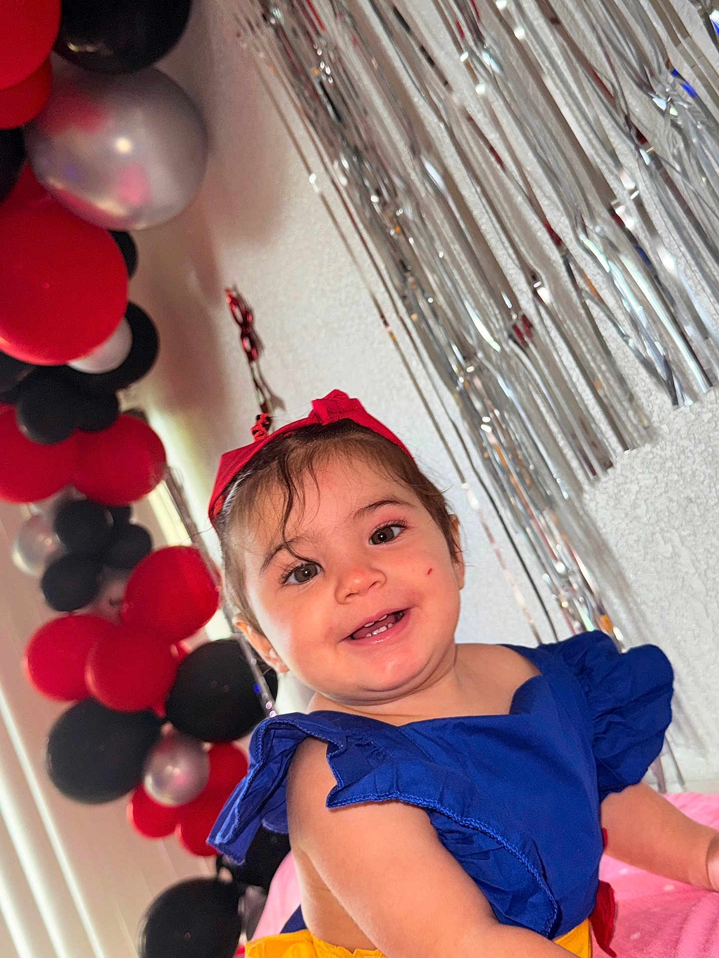 Aleska Castellano joined the competition — help win amazing prizes! balloons, blue_dress, celebration, child, colorful, cute, decorations, face, festive, happy, indoor, joyful, party, person, portrait, red_headband, silver_streamers, smiling, toddler, young_child