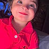 bedroom, candid, child, close_up, colorful_clothing, eyes, face, grin, hair, happy, indoors, photography, pink_shirt, polo_shirt, portrait, seated, selfie, smiling, soft_furnishings, young_person