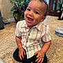 Zayden joined the competition — help win amazing prizes! toddler, child, smiling, happy, indoor, carpet, striped_shirt, black_pants, plant, home, furniture, cabinet, door, barefoot, cute, portrait, person, sitting, young_child, curly_hair