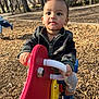 Zayden is registered to the contest to win money with this photo: toddler, child, playground, spring_rider, red, park, outdoor, autumn, fall, leaves, trees, jacket, camo, sneakers, toy, play, daylight, person, young_child, curious