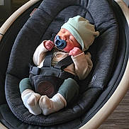 Braxton joined the competition — help win amazing prizes! baby, pacifier, hat, baby_rocker, sleeping, infant, socks, clothing, indoor, wood_floor, comfort, child, seatbelt, modern_furniture, peaceful, cute, resting, baby_girl, baby_boy, cozy