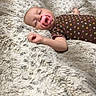 baby, bedroom, blanket, bottle, brown_onesie, child, colorful_dots, cozy, cute, furniture, home, indoors, infant, pacifier, peaceful, person, relaxing, sleeping, soft_texture, table