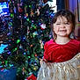 child, girl, smiling, christmas_tree, christmas_lights, ornaments, presents, holiday, festive, dress, red_clothing, indoor, celebration, happy, decorations, tree, smile, holiday_season, young_child, home