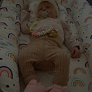 Alya participe au concours pour gagner de l'argent avec cette photo : baby, sleeping, infant, clothing, pacifier, blanket, rainbow_pattern, soft_toys, footwear, bed, cozy, cute, child, person, pink, knitwear, sleep, rest, indoors, comfort