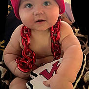 Timothy joined the competition — help win amazing prizes! baby, child, infant, red_hat, knit_cap, red_chain, plush_toy, hand, face, eyes, cheeks, skin, cute, indoor, blanket, pattern, soft_toy, football, sports_fan, smiling