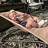 baby, infant, smile, headband, baby_bouncer, socks, carpet, living_room, furniture, chair, table, person, child, happy, indoor, floor, cute, relaxing, clothing, home