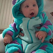 George joined the competition — help win amazing prizes! baby, child, infant, hoodie, onesie, blue, purple, soft_texture, indoor, radiator, adult_hand, carpet, curtains, light, expression, cute, warm, cozy, foot, person