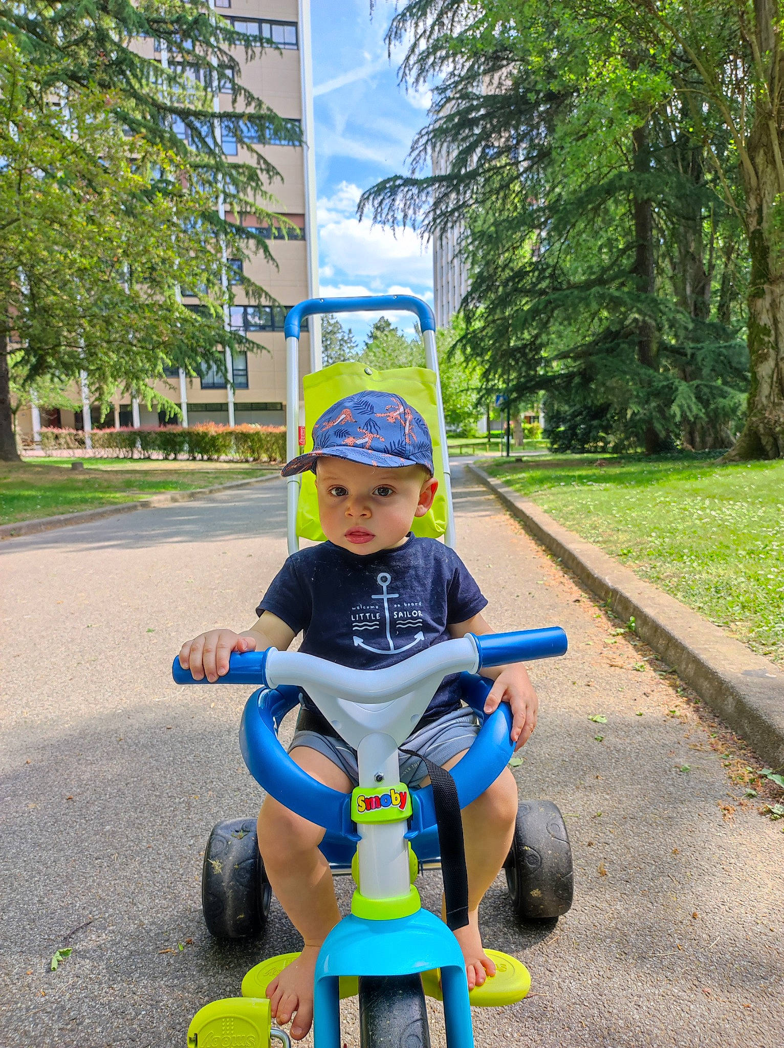 Gabriel participe au concours pour gagner de l'argent avec cette photo : asphalt, automotive_wheel_system, baby, baby_toddler_clothing, city, electric_blue, grass, headwear, helmet, leisure, person, plant, public_space, recreation, riding_toy, rolling, sky, tire, toddler, toy