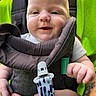 baby, child, infant, smiling, happy, face, portrait, stroller, harness, seat, outdoor, nature, green, clothing, white_shirt, adult_hand, tattoo, close_up, sitting, family