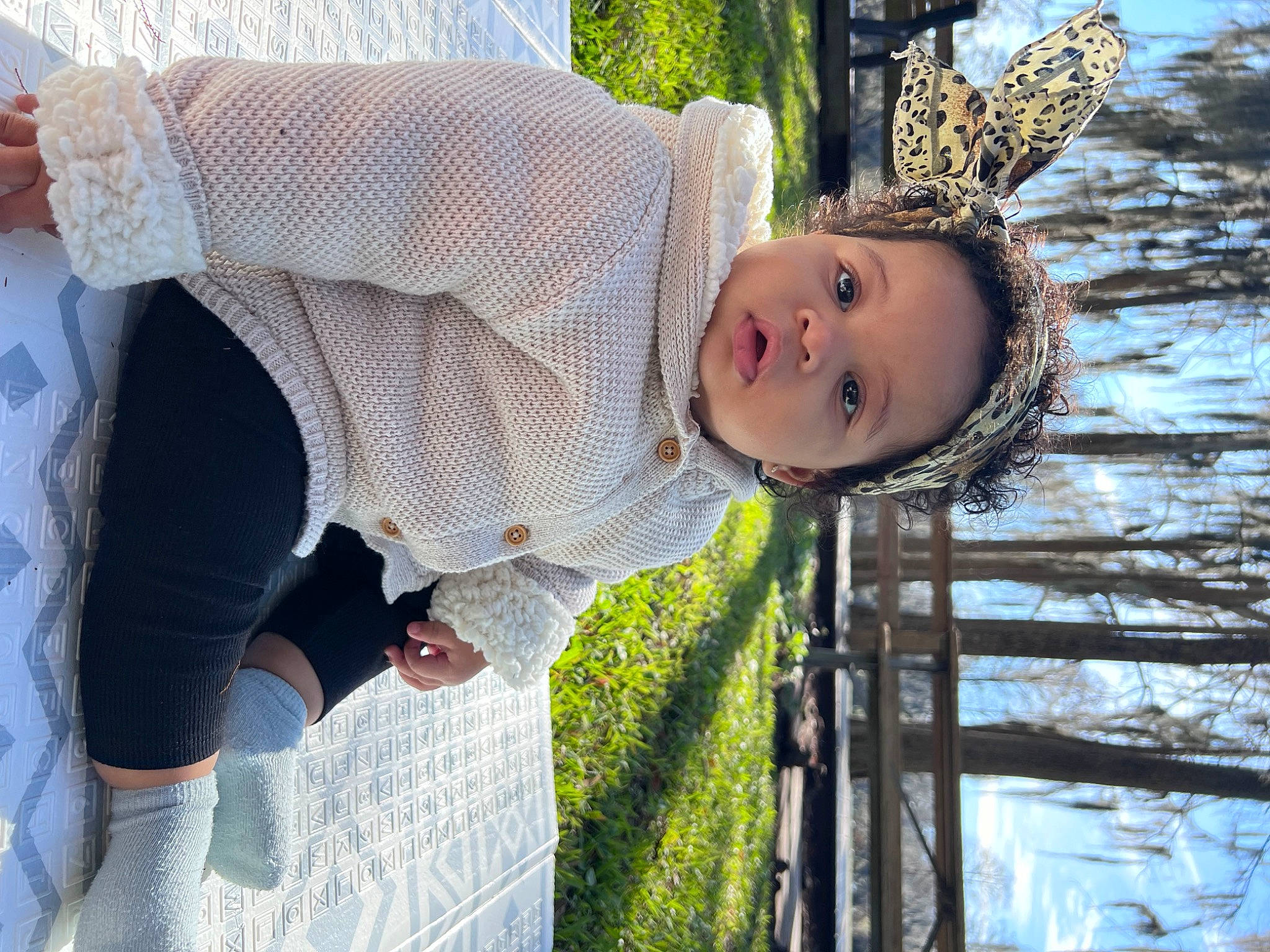 Meghan is registered to the contest to win money with this photo: baby, child, fun, grass, happy, hat, leisure, pattern, people_in_nature, person, plant, sitting, smile, sunglasses, toddler, tree, vacation, water, winter, wood