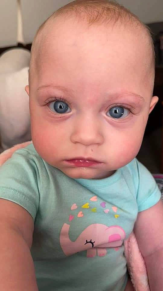 June is registered to the contest to win money with this photo: arm, baby, baby_toddler_clothing, cheek, chin, ear, eye, eyebrow, eyelash, facial_expression, forehead, hair, human_body, iris, lip, mouth, nose, organ, person, skin