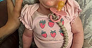 Stevie is registered to the contest to win money with this photo: baby, sleeping, pacifier, pink_clothing, onesie, hand, lap, indoor, person, infant, cute, peaceful, relaxed, skin, furniture, pattern, holding, child, human, comfort