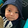 baby, child, hoodie, navy_blue, car_seat, blanket, face, eyes, baby_clothing, infant, cute, child_seat, seatbelt, indoor, portrait, young_child, person, cozy, soft_lighting, closeup
