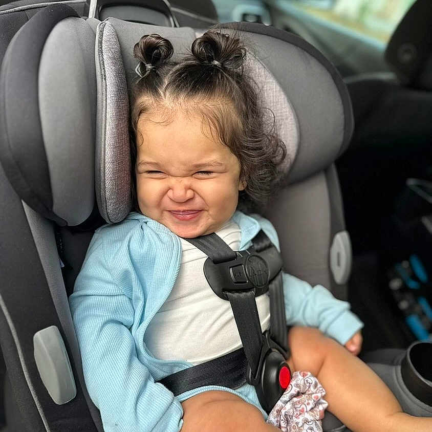 Navi is registered to the contest to win money with this photo: accessories, baby, belt, car, car_interior, carseat, clothing, cushion, face, happy, head, headrest, homedecor, person, photography, portrait, smile, t_shirt, transportation, vehicle