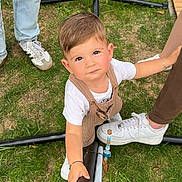 Noam participe au concours pour gagner de l'argent avec cette photo : casual_clothing, child, curious, cute, daylight, grass, greenery, ground, holding, legs, looking_up, metal_bar, outdoor, overalls, people, playing, sneakers, toddler, white_shirt, young_child