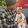 Zoe joined the competition — help win amazing prizes! baby, child, man, outdoor, camping, tent, sunlight, smile, beanie, plaid_shirt, pink_onesie, forest, trees, pacifier, happy, holding, nature, portrait, family, warm_clothing