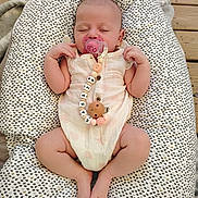 Cassie participe au concours pour gagner de l'argent avec cette photo : baby, sleeping, pacifier, onesie, heart_pattern, baby_lounger, cushion, wooden_deck, infant, cute, peaceful, relaxed, hands_up, legs_crossed, soft_fabric, pink, white, patterned, outdoor, resting