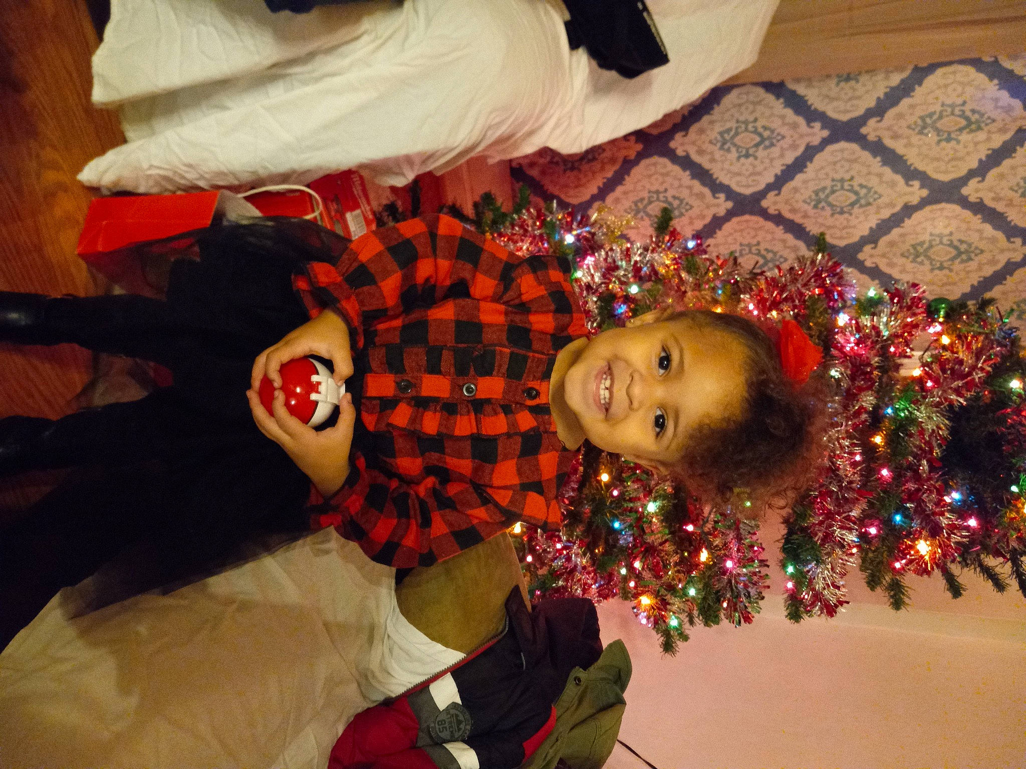 Gemma joined the competition — help win amazing prizes! carmine, child, christmas, christmas_eve, christmas_ornament, christmas_tree, event, facial_expression, fun, happy, holiday, holiday_ornament, joy, ornament, person, plant, red, room, toddler, tradition