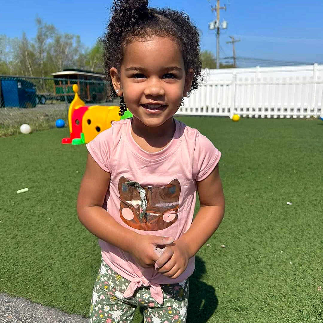 Alita is registered to the contest to win money with this photo: ball, baseball, baseballball, blackhair, child, clothing, curlyhair, face, female, girl, hair, head, nature, outdoors, person, sleeve, sport, tennis, tennisball, yard