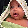 baby, child, towel, hood, polka_dots, face, skin, expression, curious, infant, closeup, person, portrait, indoors, soft_texture, mouth_open, eyes, head, wrapped, cute