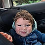 baby, car_interior, car_seat, child, curly_hair, cute, denim_jacket, face, greenery, hand, happy, indoors, portrait, seatbelt, smiling, teether, toddler, toy, window, young_child