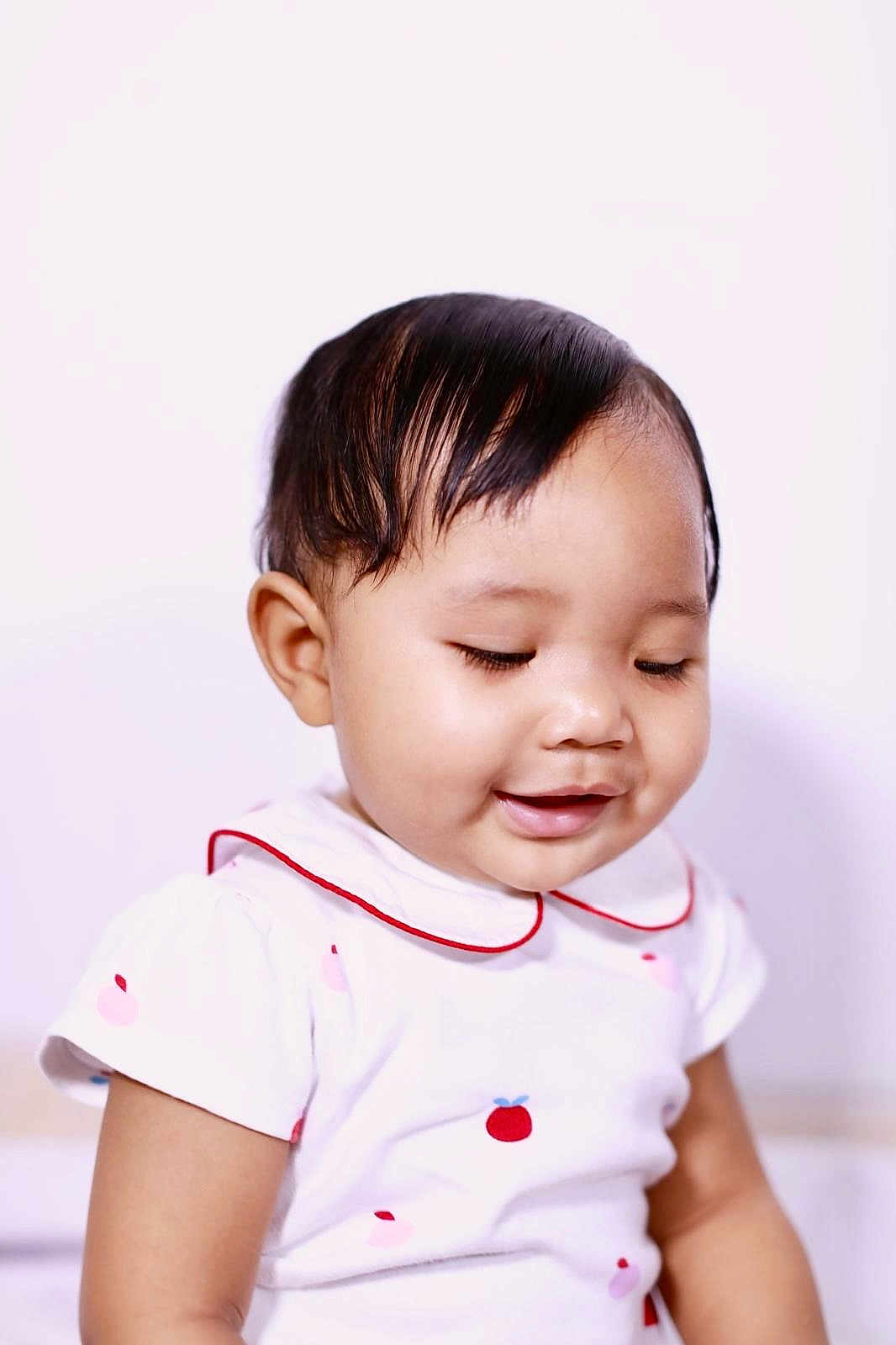 Stella participe au concours pour gagner de l'argent avec cette photo : baby, infant, child, portrait, smile, smiling, short_hair, black_hair, collar, white_background, soft_lighting, close_up, eyelashes, cheek, dress, sitting, cute, happy, skin, studio_photo