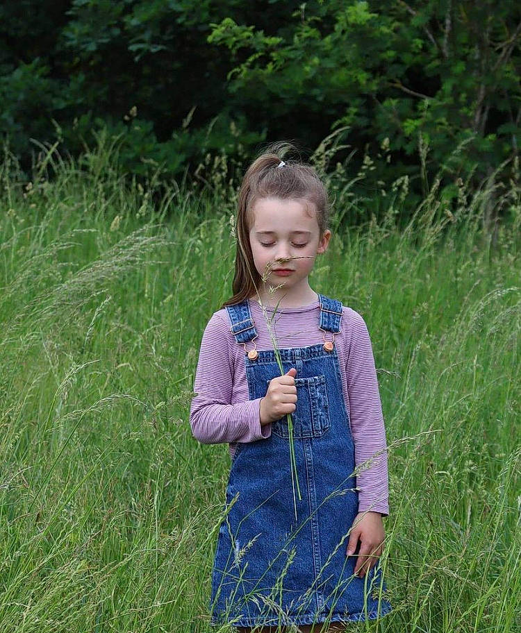 Athena is registered to the contest to win money with this photo: baby_toddler_clothing, day_dress, dress, electric_blue, grass, grass_family, grassland, hair, happy, meadow, pattern, people_in_nature, person, plant, prairie, purple, shrub, sleeve, summer, terrestrial_plant