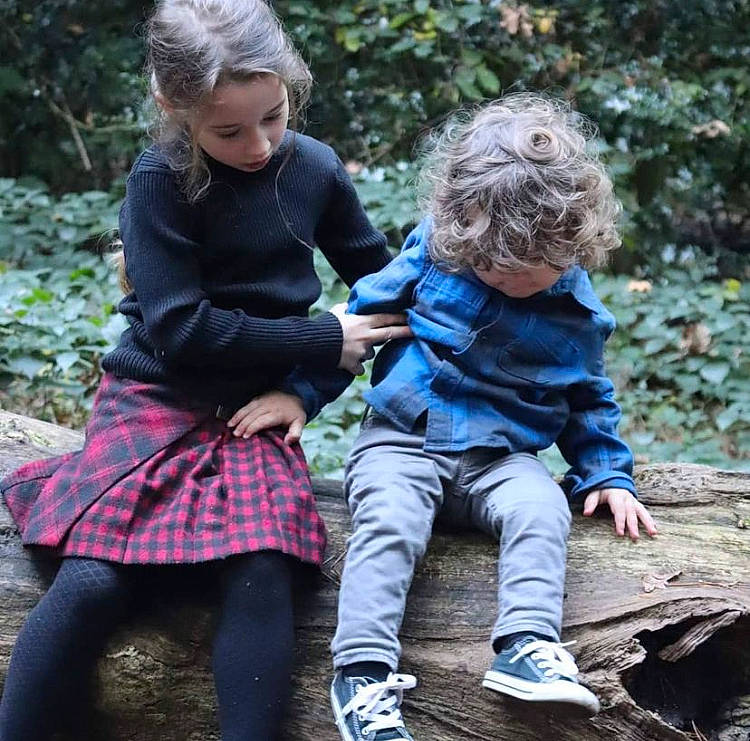 Athena joined the competition — help win amazing prizes! baby, baby_toddler_clothing, boot, child, gesture, grass, hair, head, outerwear, pattern, people_in_nature, person, plant, shoe, sitting, sleeve, sock, tartan, toddler, tree