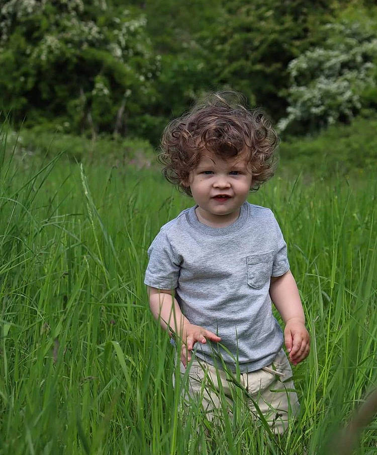 Oakley is registered to the contest to win money with this photo: agriculture, baby_toddler_clothing, child, field, fun, grass, grass_family, grassland, happy, hierochloe, landscape, meadow, natural_landscape, pasture, people_in_nature, person, plant, prairie, sitting, t_shirt