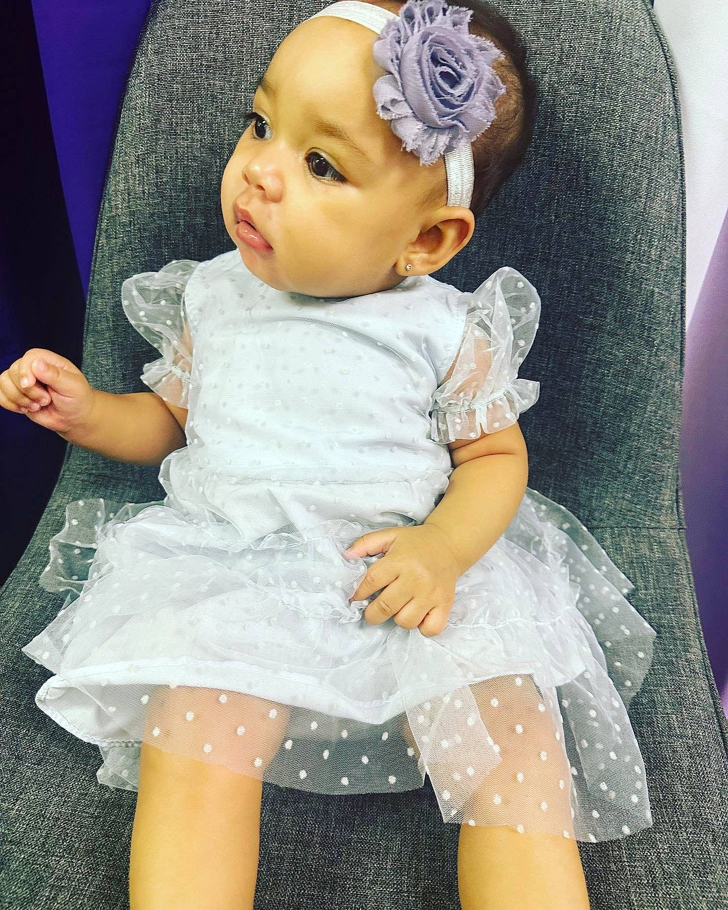 Arianna is registered to the contest to win money with this photo: baby, baby_toddler_clothing, blue, cap, cheek, chin, costume_hat, day_dress, dress, happy, human_body, iris, person, pink, purple, skin, sleeve, textile, toddler, violet