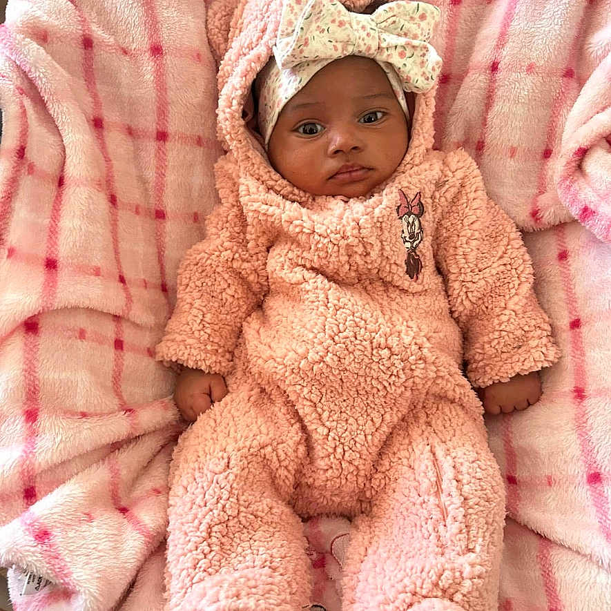 Layla joined the competition — help win amazing prizes! baby, blanket, bow, child, clothing, cozy, cute, face, headwear, indoors, infant, newborn, onesie, person, pink, portrait, resting, sleepwear, soft_texture, warm