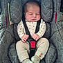 baby, sleeping, car_seat, infant, child, clothing, straps, harness, red_buckle, gray, patterned_clothing, cozy, cute, hands, feet, socks, upholstery, comfort, peaceful, portrait