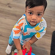 Viraj is registered to the contest to win money with this photo: toddler, child, toy, walker, floor, wooden_floor, indoor, clothing, colorful, hands, face, person, young_child, curious, standing, play, bright_colors, socks, short_sleeve_shirt, blue_pants