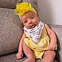 arms, baby, bandana, child, couch, cute, floral_pattern, gray_fabric, headband, indoors, infant, legs, playful, portrait, sitting, skin, textured_fabric, tongue_out, white_wall, yellow_dress