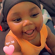 Jah'Mir joined the competition — help win amazing prizes! baby, child, smiling, tongue_out, cap, orange_clothing, indoor, face, happy, cute, person, infant, skin, headwear, portrait, closeup, furniture, blurred_background, pink_heart, text_overlay